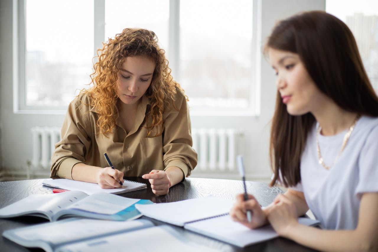 Young women collaborating on a study project in a bright room.